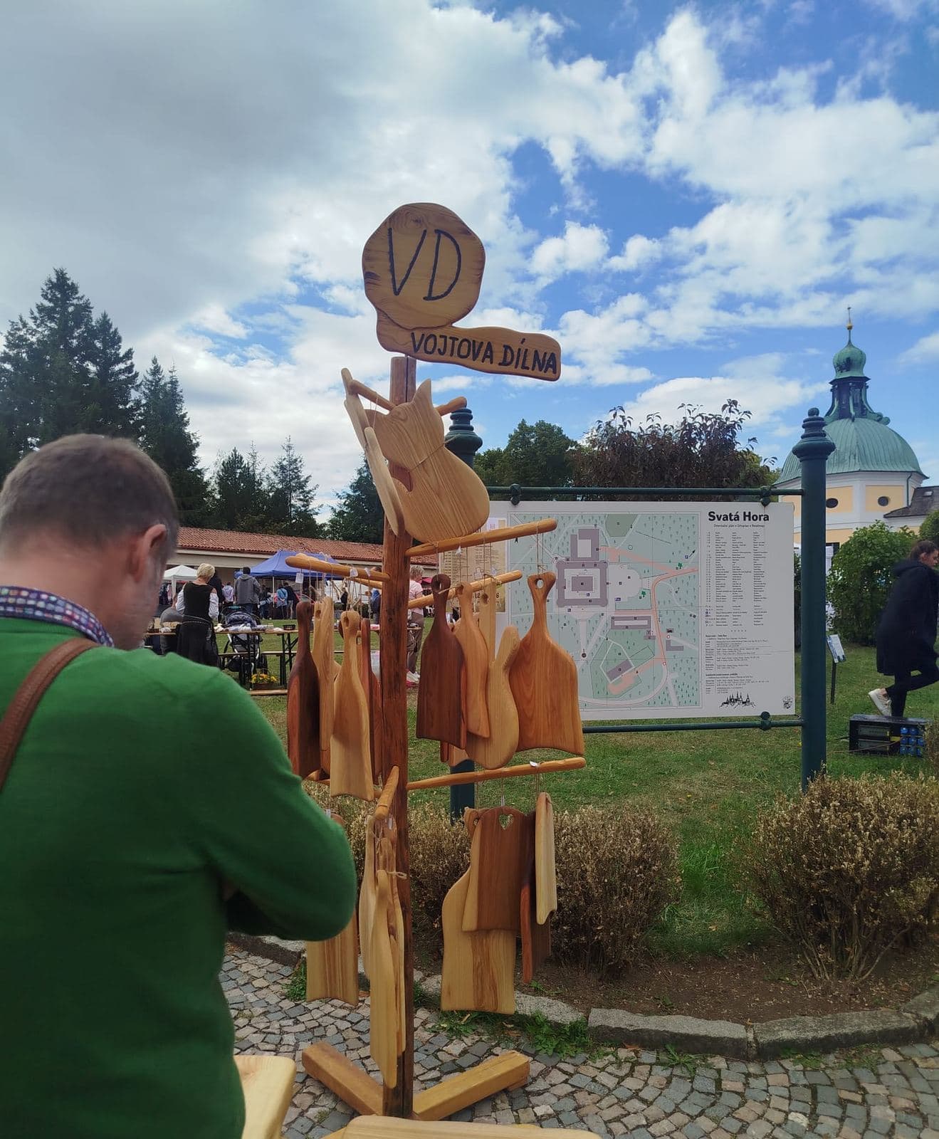 Ruční dřevěné výrobky ve stánku, v pozadí věže baziliky